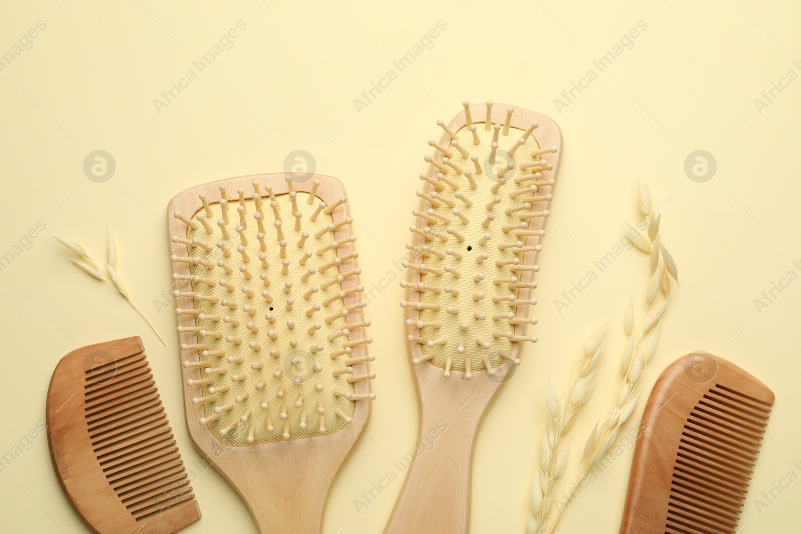 Photo of Wooden hair brushes, combs and spikes on beige background, flat lay