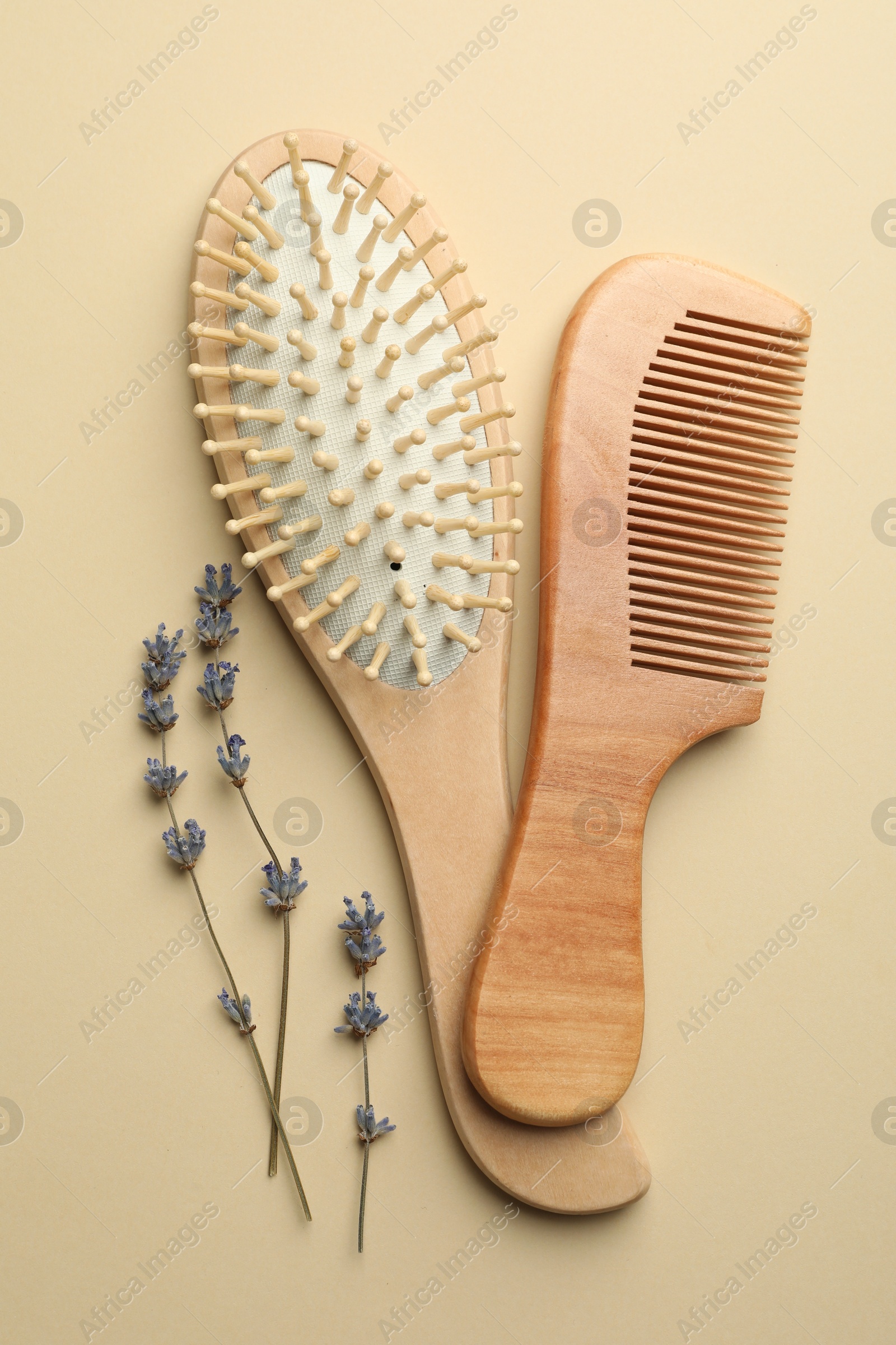 Photo of Hair brush, comb and lavender flowers on beige background, top view