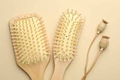 Photo of Wooden hair brushes and poppy heads on beige background, top view