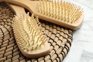 Photo of Wooden hair brushes on white marble background, closeup