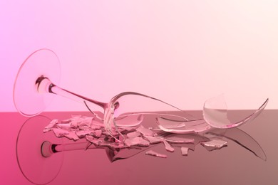 Photo of Pieces of broken wine glass on table, closeup. Color tone effect