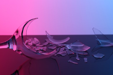 Photo of Pieces of broken wine glass on table, closeup. Color tone effect