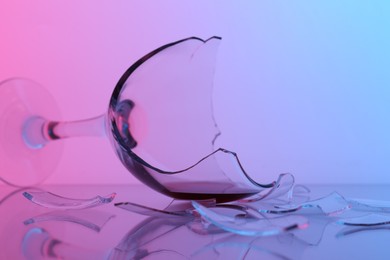 Photo of Pieces of broken glass with wine on table, closeup. Color tone effect