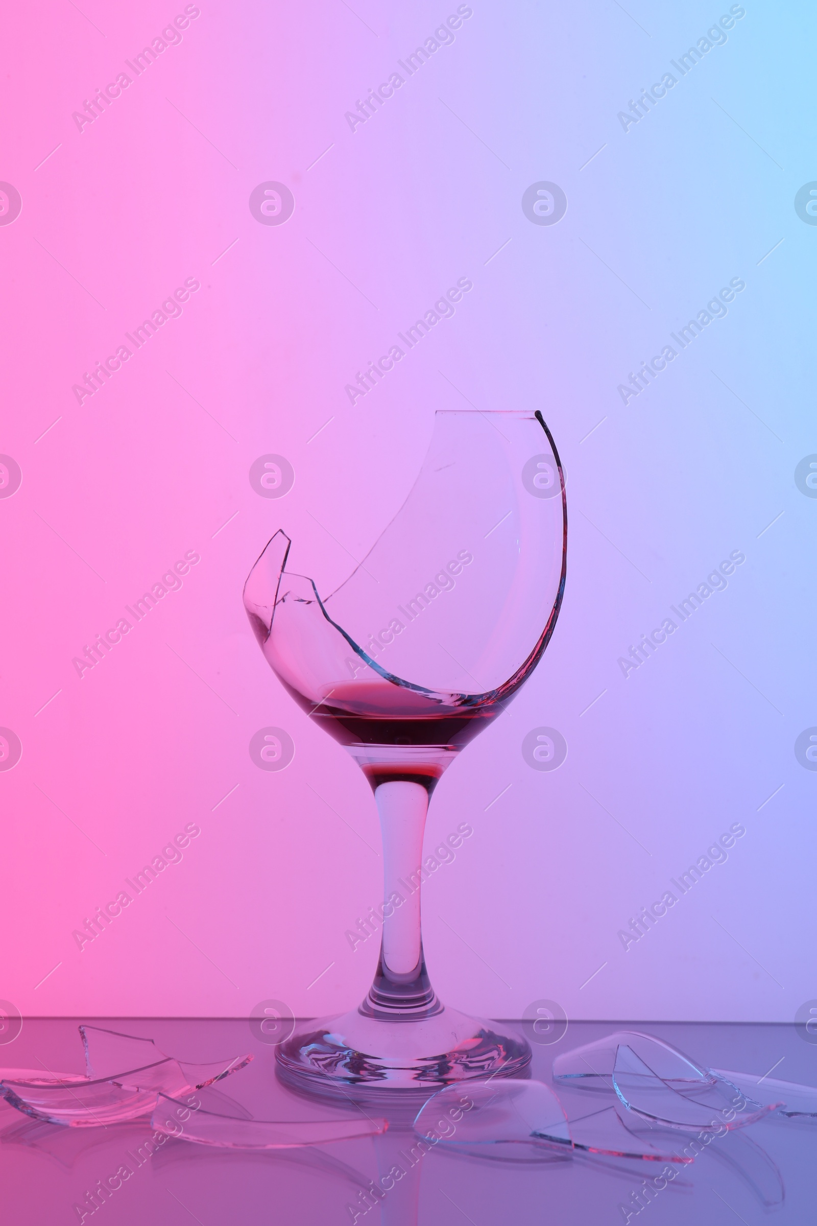 Photo of Pieces of broken glass with wine on table, color tone effect