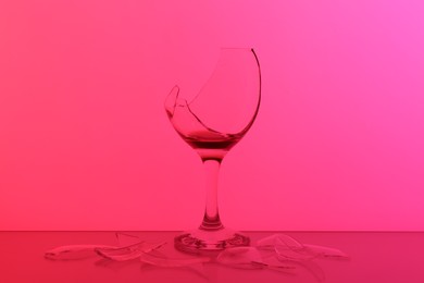 Photo of Pieces of broken glass with wine against hot pink background, color tone effect