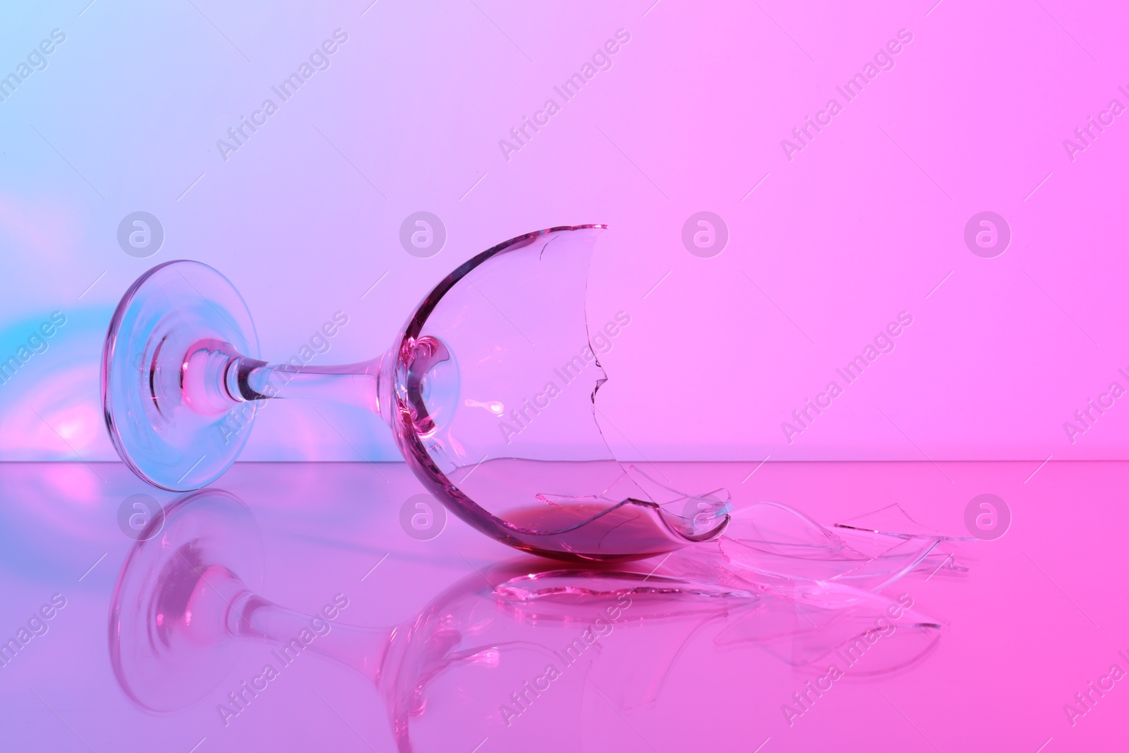 Photo of Pieces of broken glass with wine on table, closeup. Color tone effect