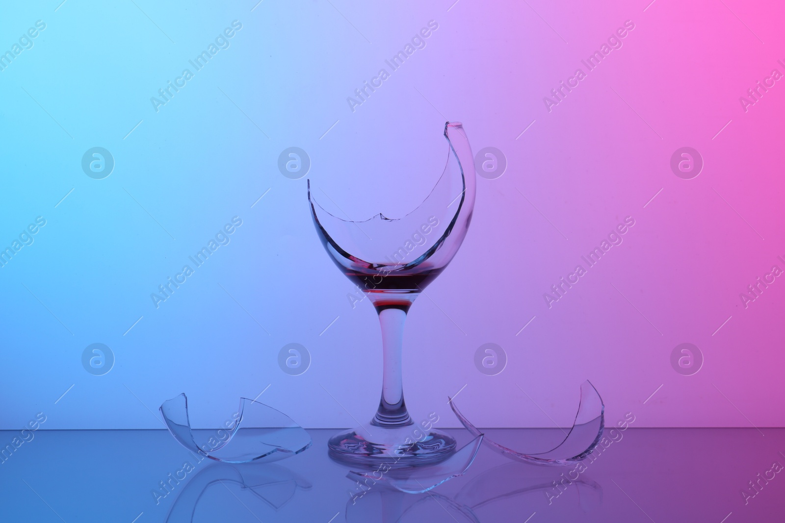 Photo of Pieces of broken glass with wine on table, color tone effect