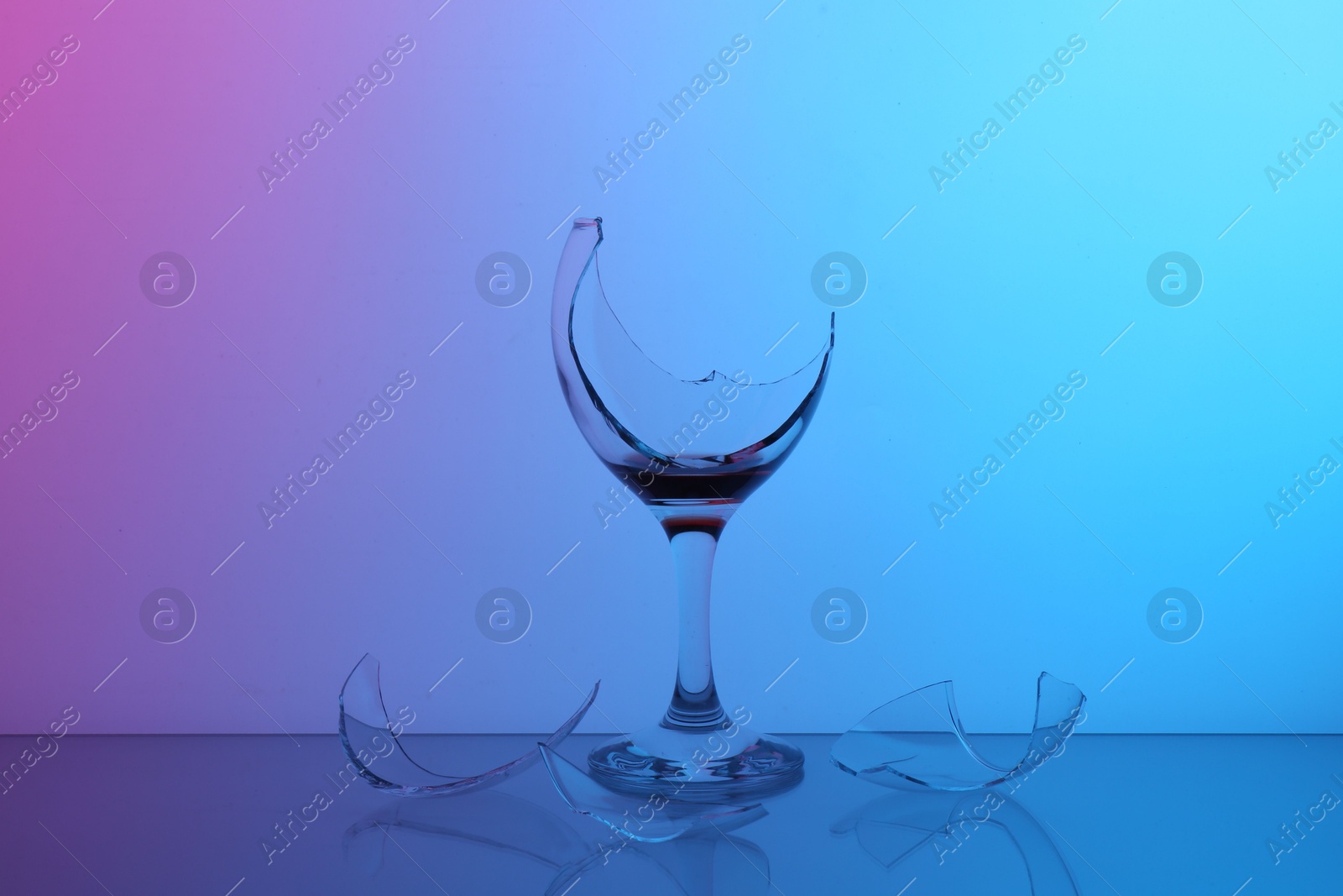 Photo of Pieces of broken glass with wine on table, color tone effect