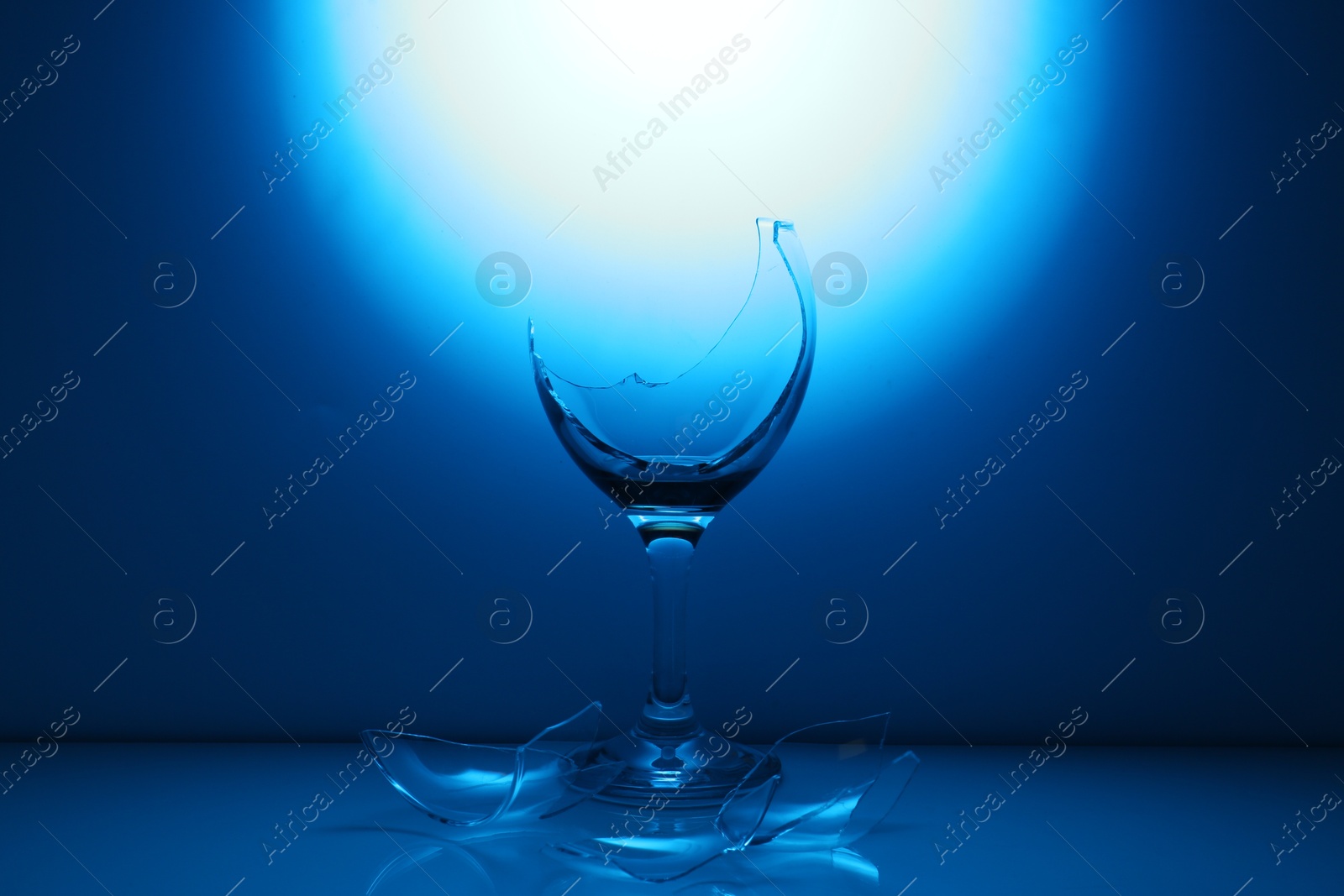 Photo of Pieces of broken wine glass against dark blue gradient background