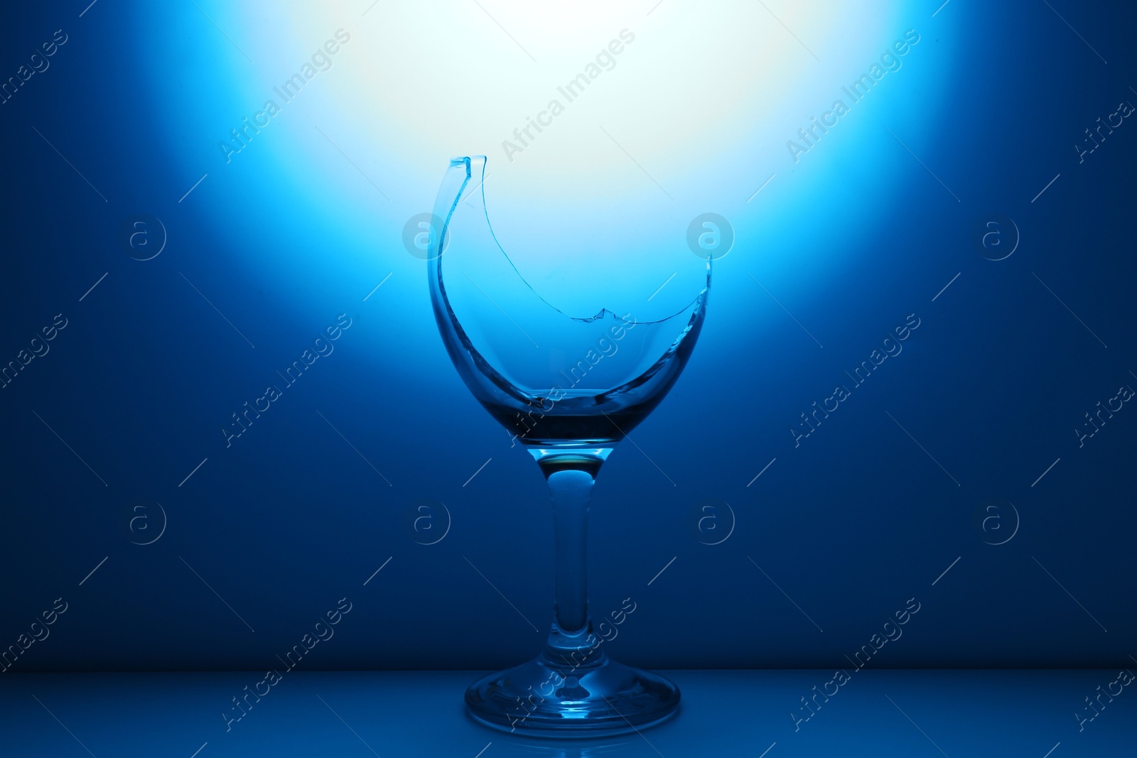 Photo of Broken wine glass against dark blue gradient background