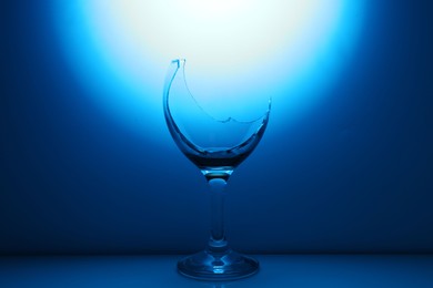 Photo of Broken wine glass against dark blue gradient background