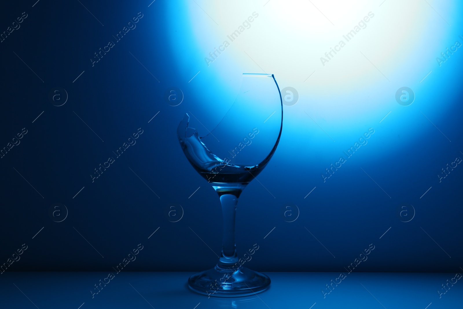 Photo of Broken wine glass against dark blue gradient background