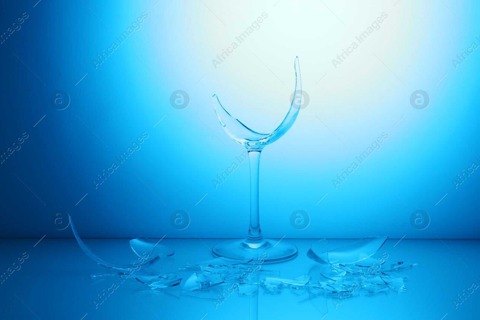 Photo of Pieces of broken wine glass against light blue gradient background