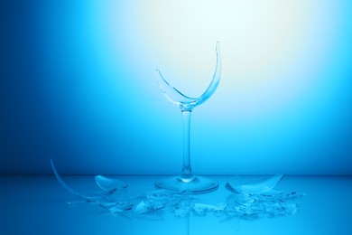 Photo of Pieces of broken wine glass against light blue gradient background