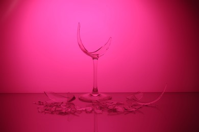 Photo of Pieces of broken wine glass against deep pink background, color tone effect