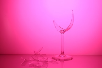 Photo of Pieces of broken wine glass against magenta gradient background, color tone effect