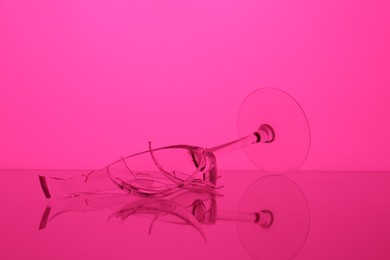 Photo of Pieces of broken wine glass against magenta background, color tone effect