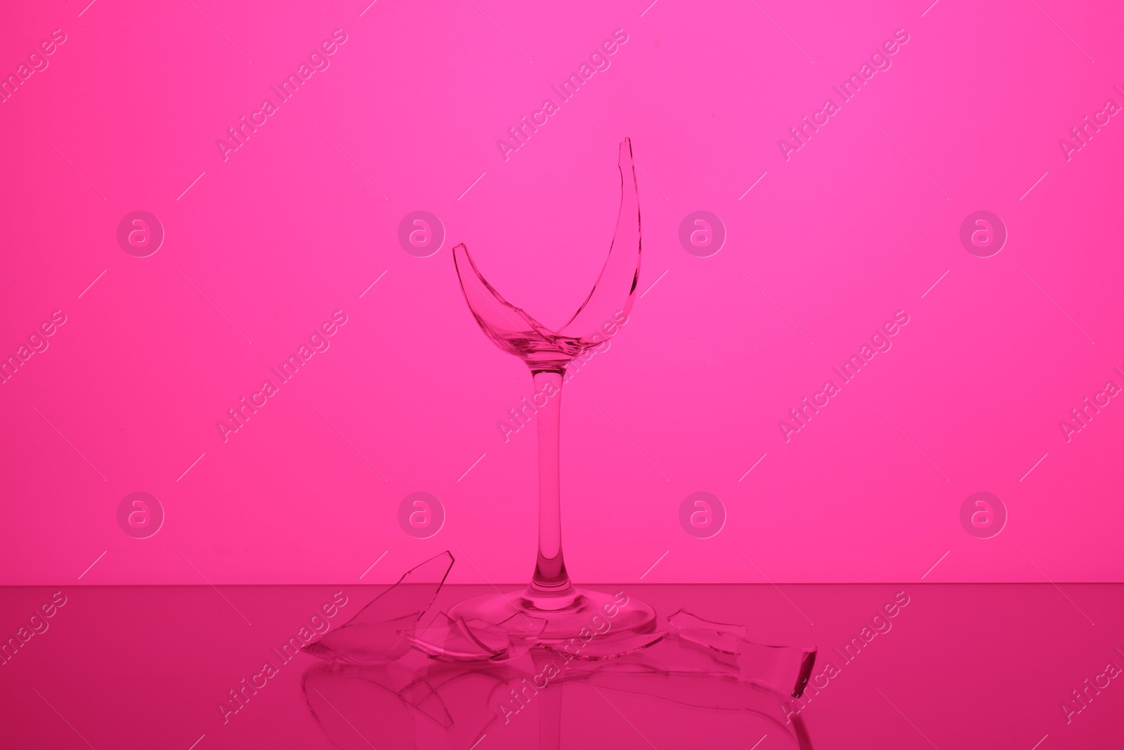 Photo of Pieces of broken wine glass against magenta background, color tone effect