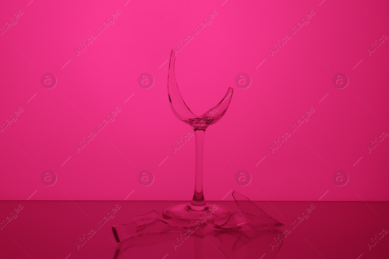 Photo of Pieces of broken wine glass against magenta background, color tone effect