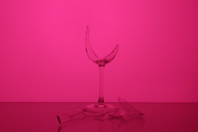 Photo of Pieces of broken wine glass against magenta background, color tone effect