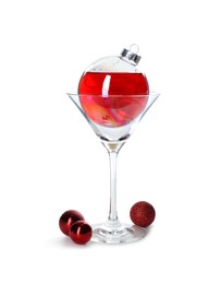 Photo of Presentation of Christmas cocktail in bauble and glass on white background