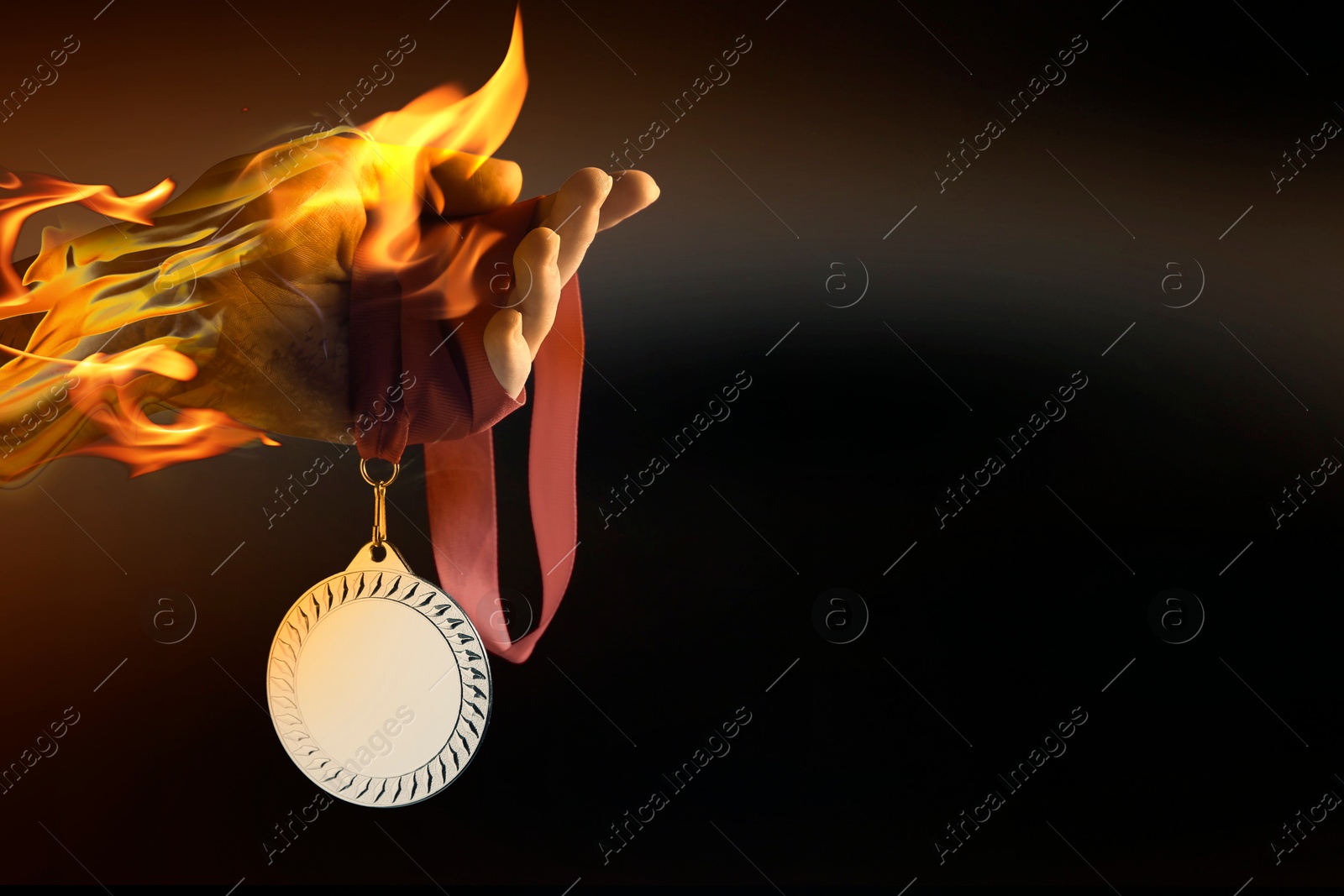 Image of Woman holding silver medal in her flaming hand on black background, closeup. Space for text