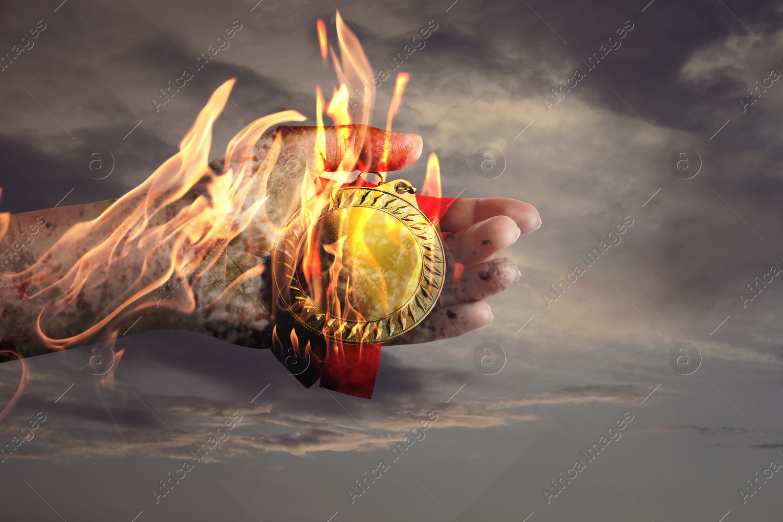 Image of Woman holding gold medal in her flaming hand against darkened sky, closeup