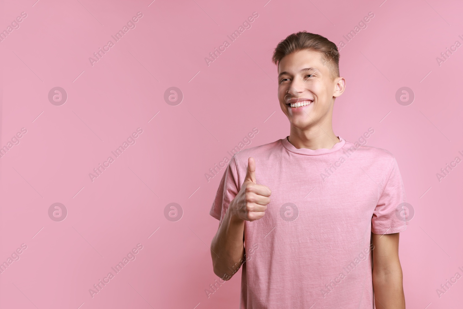 Photo of Happy man showing thumbs up on pink background, space for text. Like gesture