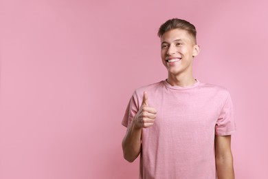 Photo of Happy man showing thumbs up on pink background, space for text. Like gesture