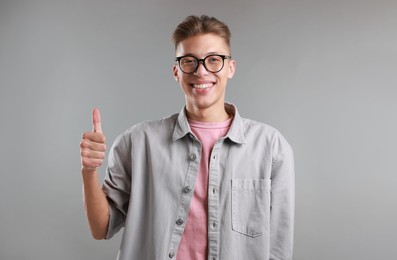 Photo of Happy man showing thumbs up on grey background. Like gesture