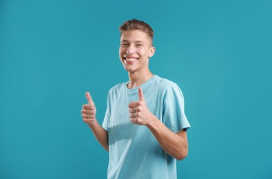 Photo of Happy man showing thumbs up on light blue background. Like gesture