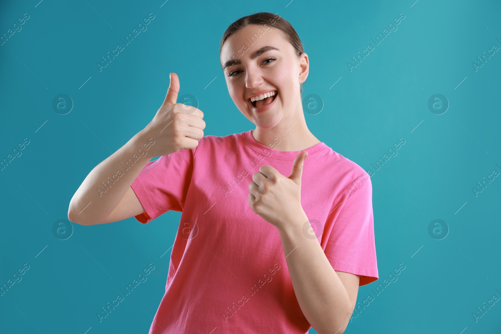 Photo of Happy woman showing thumbs up on light blue background. Like gesture