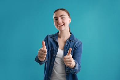 Photo of Happy woman showing thumbs up on light blue background. Like gesture