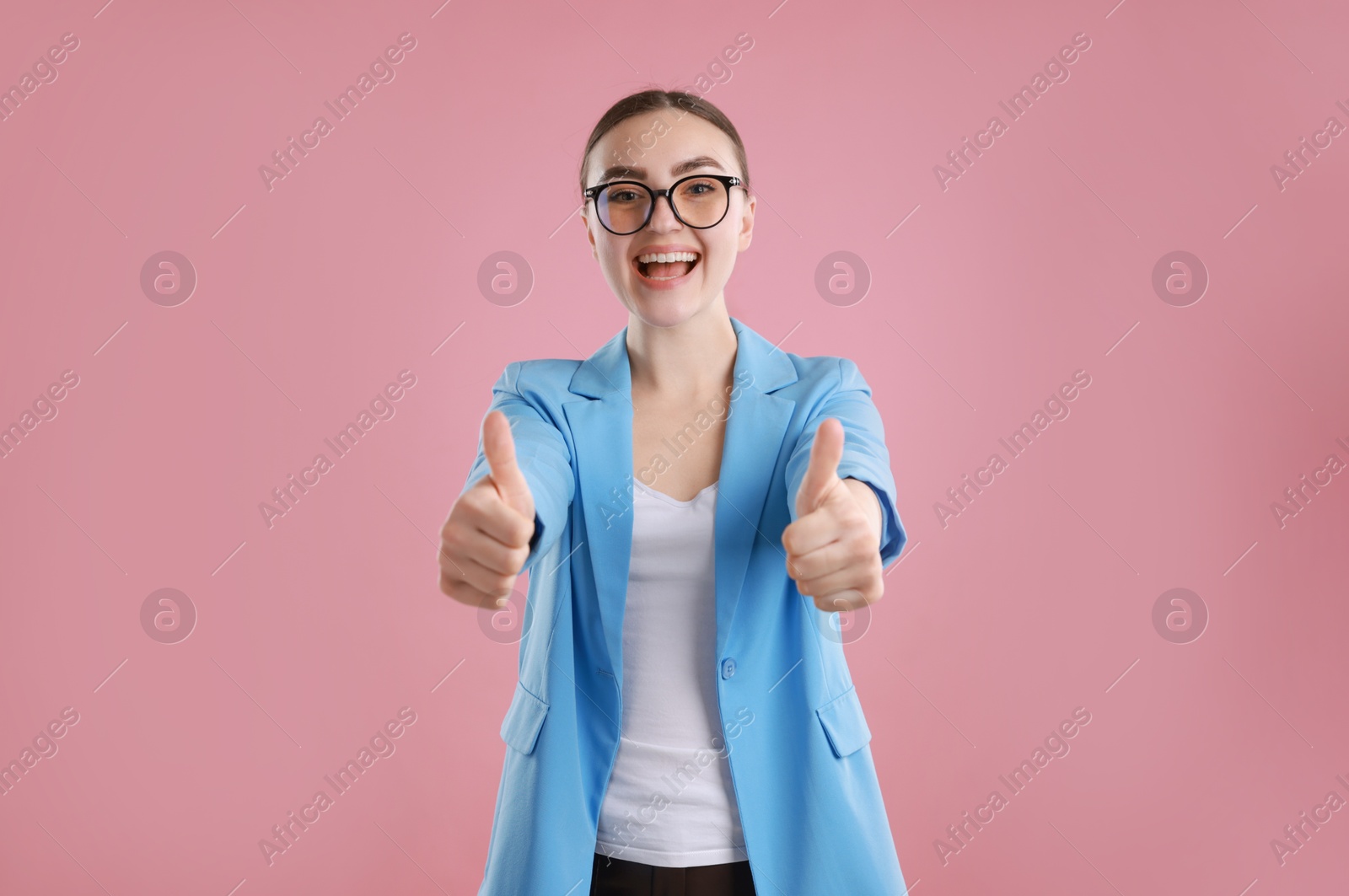 Photo of Happy woman showing thumbs up on pink background. Like gesture