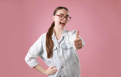 Photo of Happy woman showing thumbs up on pink background. Like gesture