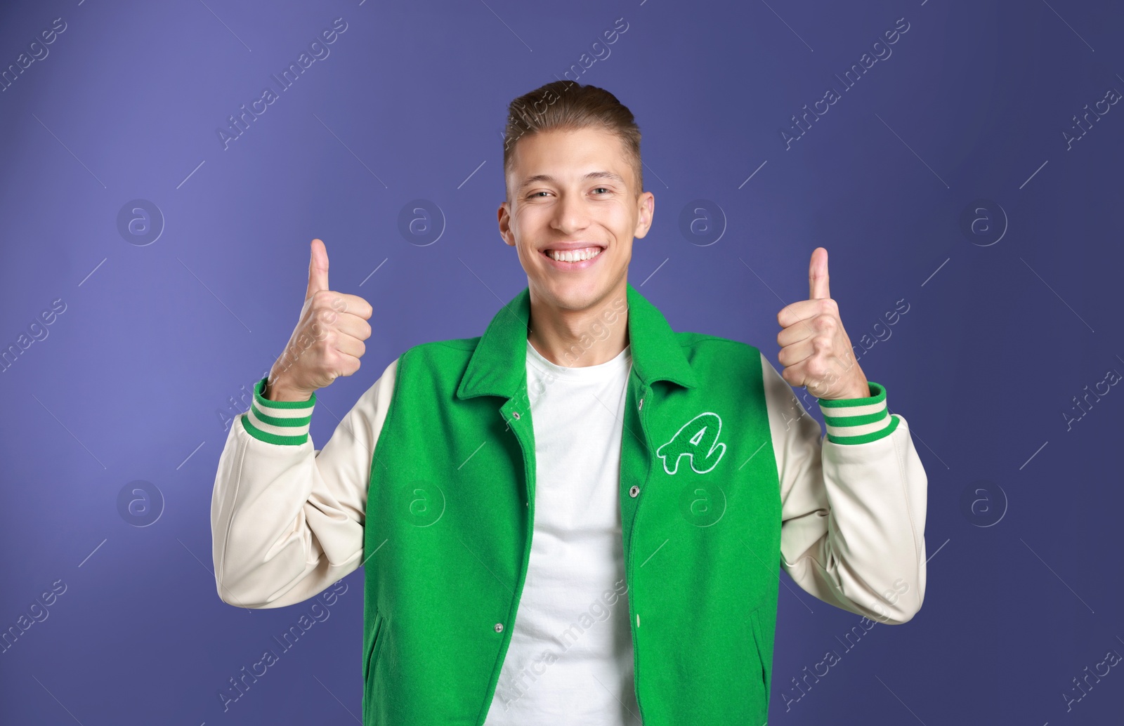 Photo of Happy man showing thumbs up on purple background. Like gesture