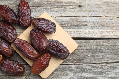 Photo of Many tasty dried dates on wooden table, top view. Space for text