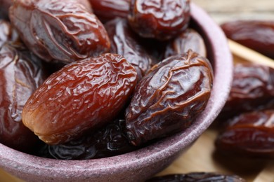 Photo of Many tasty dried dates in bowl on table, closeup