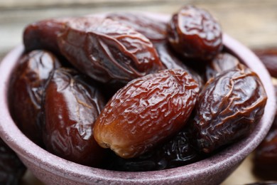 Photo of Many tasty dried dates in bowl on table, closeup