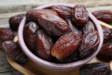 Photo of Many tasty dried dates in bowl on table, closeup