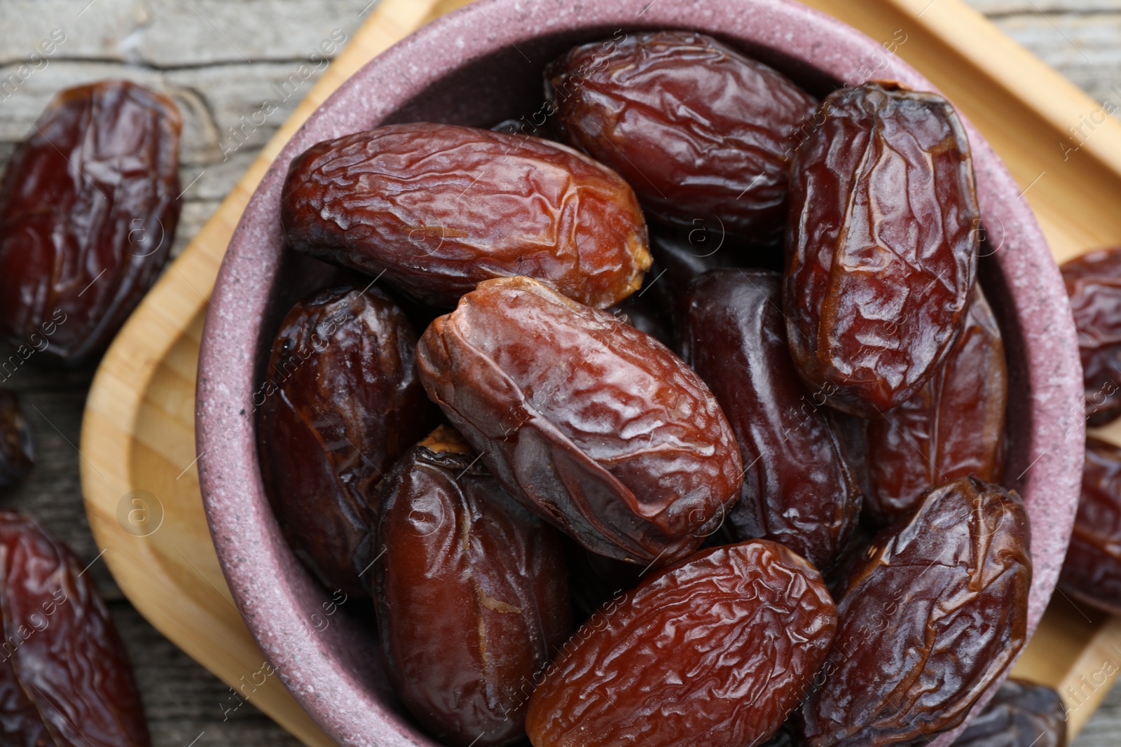 Photo of Many tasty dried dates in bowl on table, top view