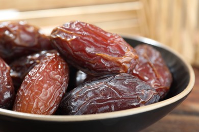 Photo of Many tasty dried dates in bowl on table, closeup