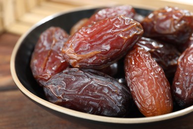 Photo of Many tasty dried dates in bowl on table, closeup