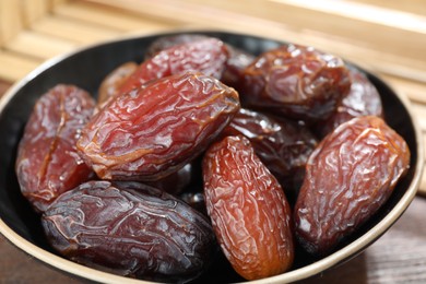 Photo of Many tasty dried dates in bowl on table, closeup