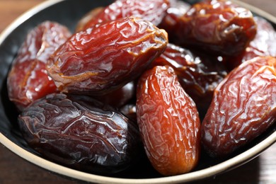 Photo of Many tasty dried dates in bowl on table, closeup