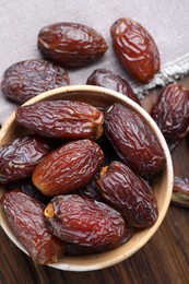 Photo of Many tasty dried dates in bowl on wooden table, top view