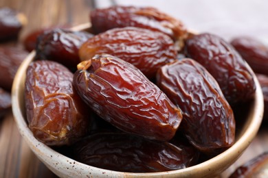 Photo of Many tasty dried dates in bowl on table, closeup