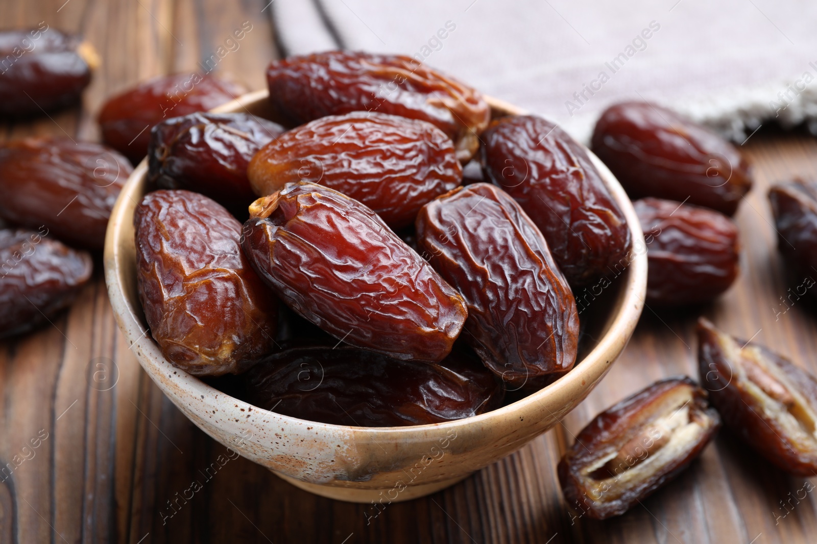 Photo of Many tasty dried dates in bowl on wooden table, closeup