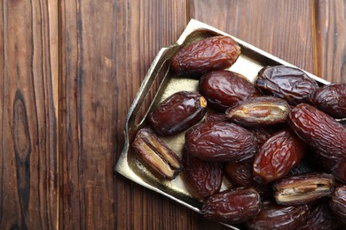 Photo of Many tasty dried dates on wooden table, top view. Space for text