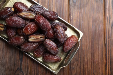 Photo of Many tasty dried dates on wooden table, top view. Space for text